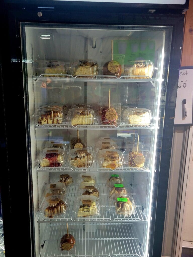 A commercial refrigerated display case filled with various baked goods and food items arranged on multiple shelves.