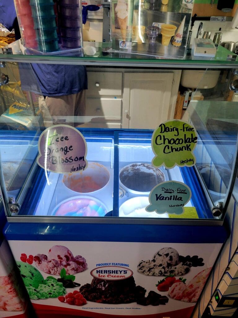 A frozen yogurt shop display case featuring white serving containers with flavor signs and toppings visible in the counter.