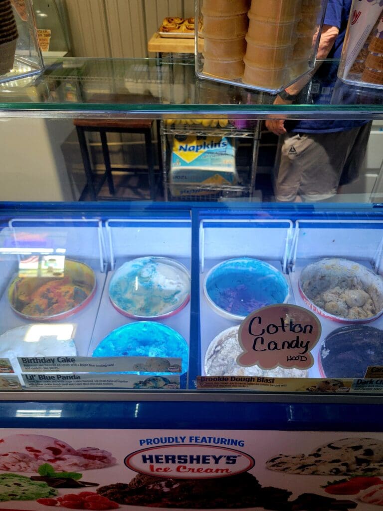A refrigerated bakery display case showcasing colorful cupcakes and desserts with Hershey's branding visible at the bottom.