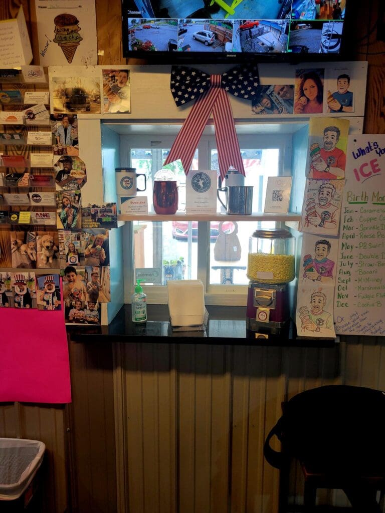 An indoor workshop or office space featuring a cluttered bulletin board decorated with colorful posters, holiday ornaments, and various papers pinned to the wall above a radiator.