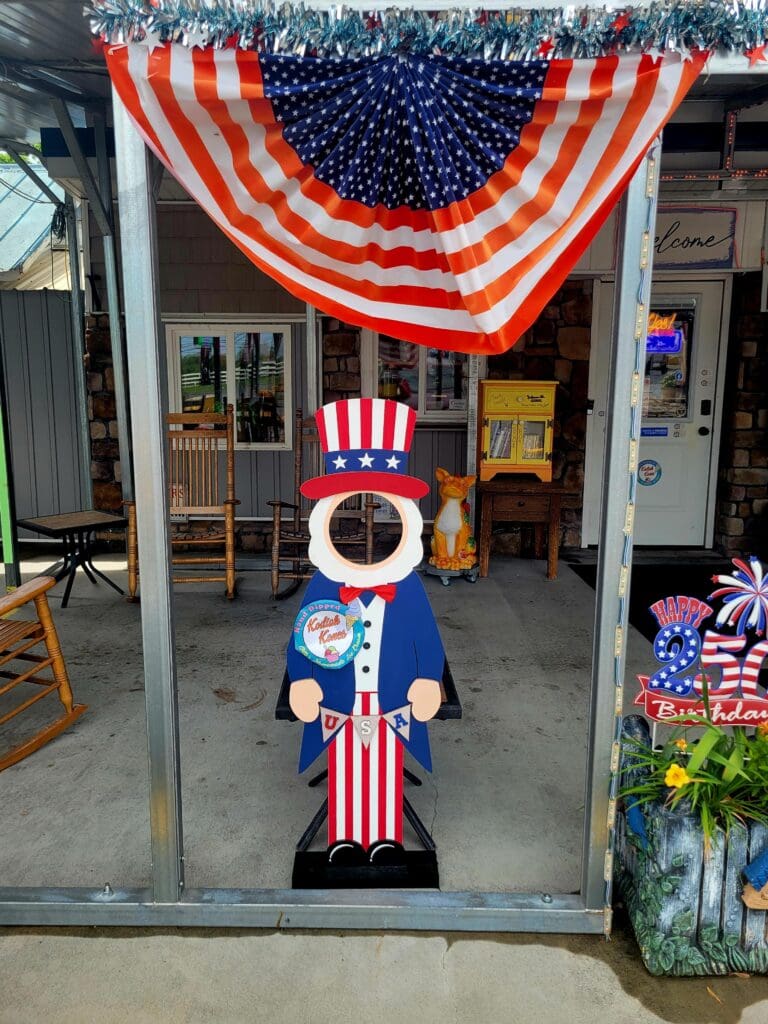 A storefront entrance decorated with patriotic Uncle Sam figure and red-white-blue bunting celebrating American independence or national holiday.