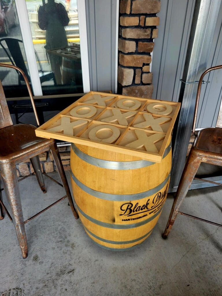 A repurposed Pabst Blue Ribbon beer barrel converted into a table with a wooden top compartmentalized into squares, displayed in a workshop or vintage furniture space.