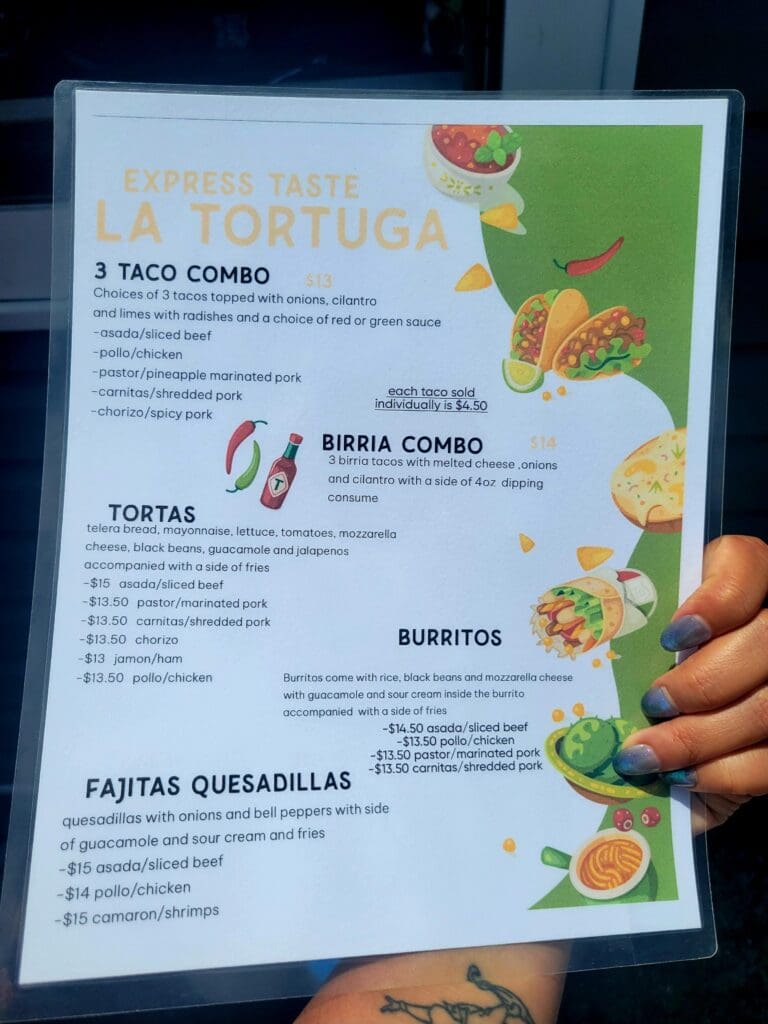A person holds up a colorful Spanish-language restaurant menu displaying taco, burrito, and quesadilla options with appetizing food photography.