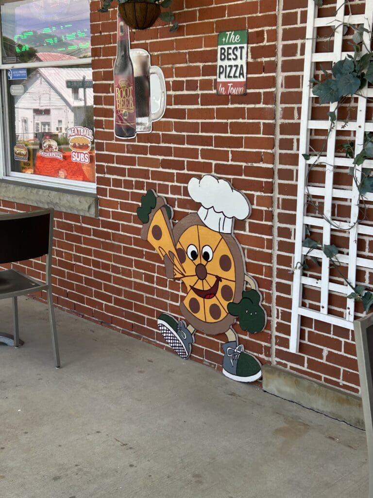 A brick storefront entrance features decorative signage and yellow artwork mounted on the exterior wall.