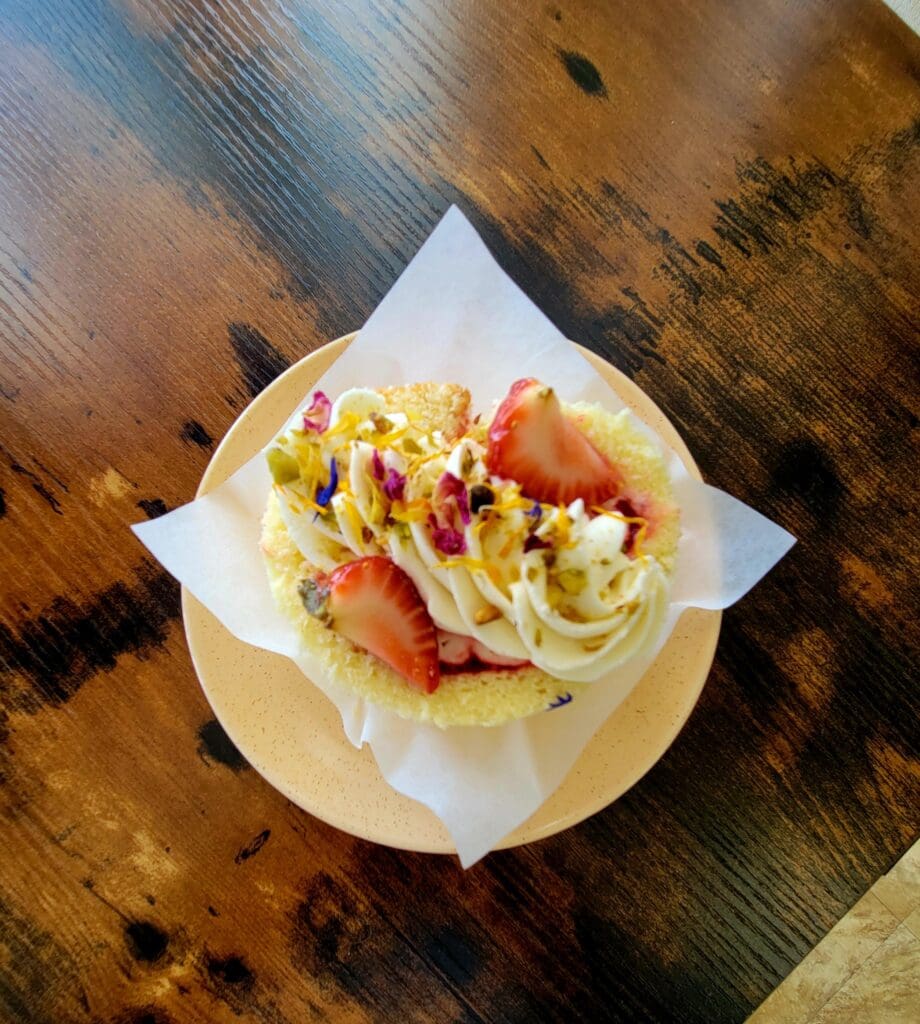 An overhead view of a fresh salad wrap with lettuce, tomato, and bacon served on a white plate on a rustic wooden surface.