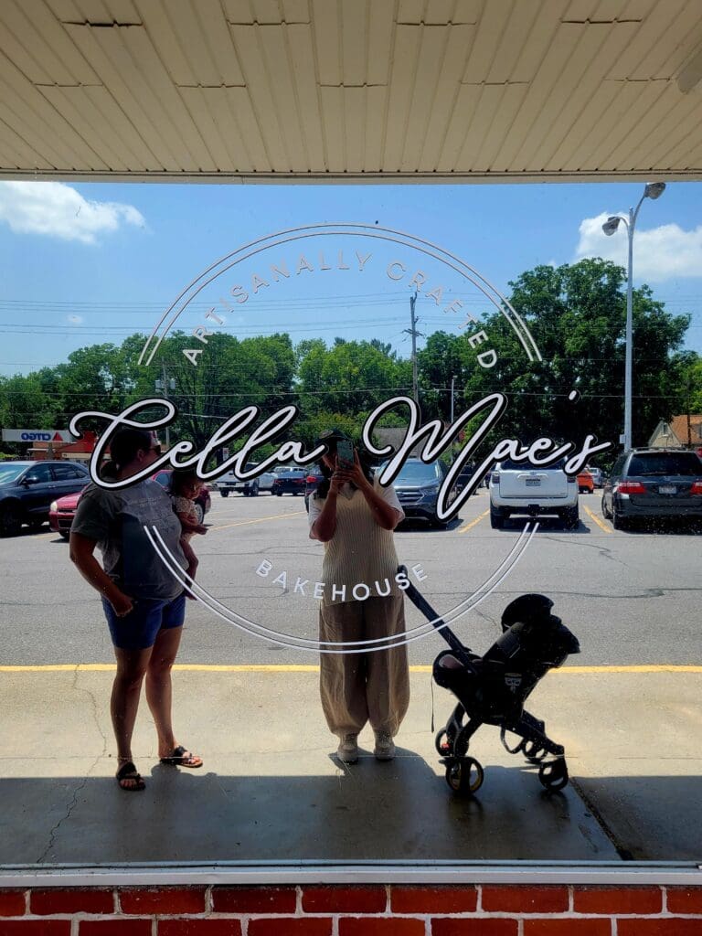 Three pageant contestants pose outdoors with a black poodle in front of a storefront with 'Bella Viper' signage visible on the window.