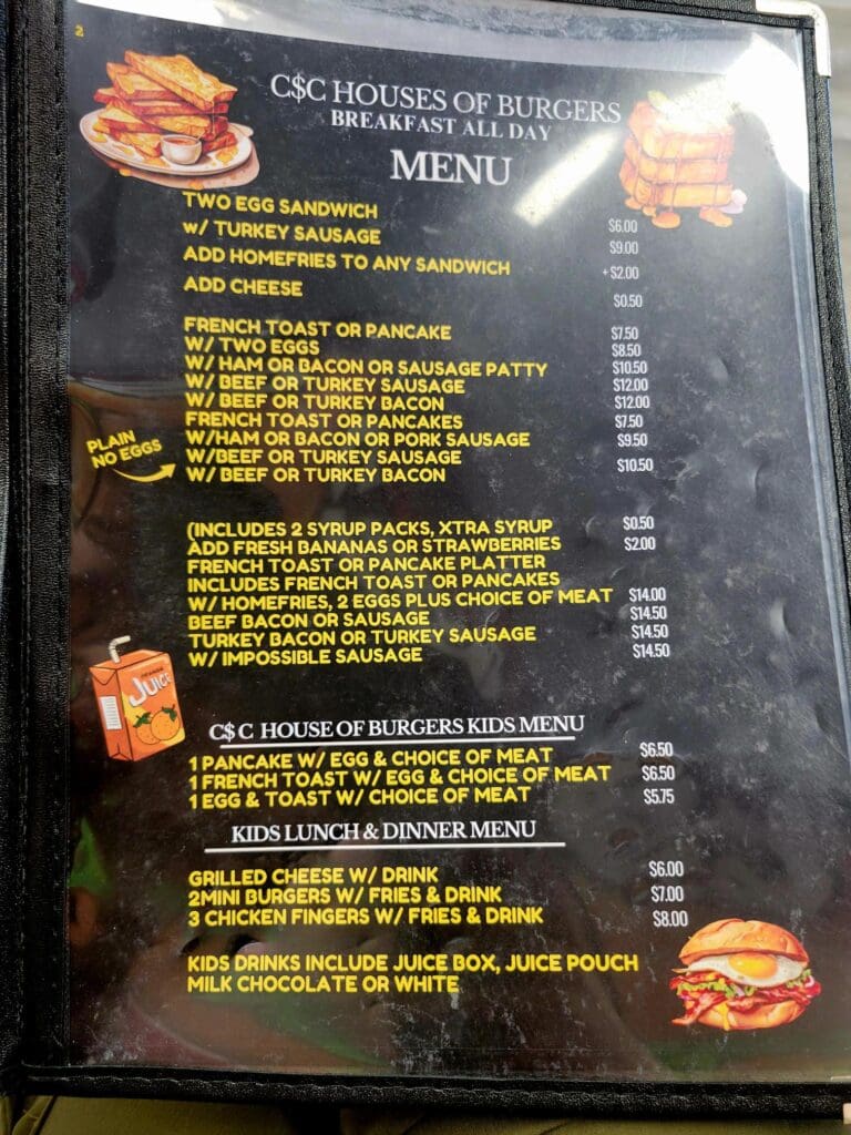 A close-up photograph of a restaurant menu board featuring BBQ and grilled meat dishes with yellow text on a dark background.