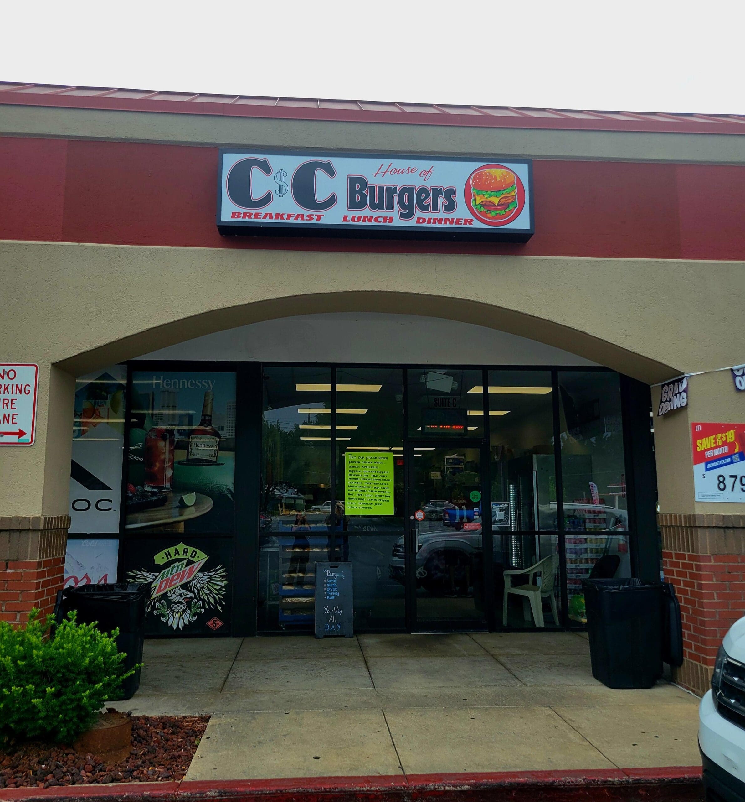 A CC Burgers fast-casual restaurant storefront with a maroon and cream exterior, glass entry doors, and signage displayed during daytime.