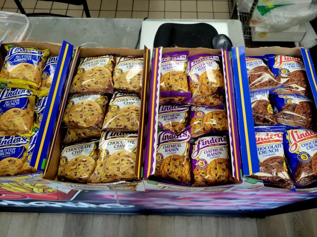 An overhead view of multiple packaged baked goods and snacks arranged in cardboard trays with blue and colorful packaging.