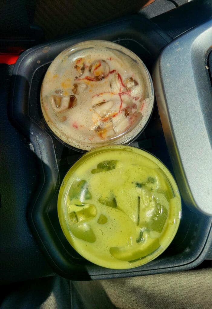 Overhead view of two food containers with beige hummus or dip in the upper container and a vibrant green sauce or dip in the lower container.