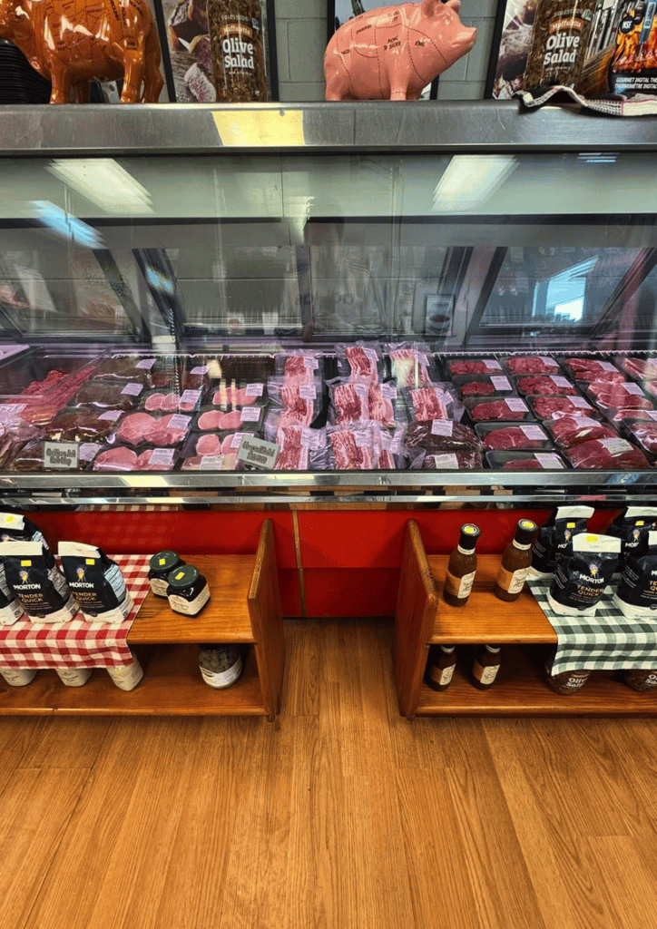 An indoor livestock auction display showcasing cattle arranged in a glass-enclosed arena with wooden flooring and checkered pattern accents.