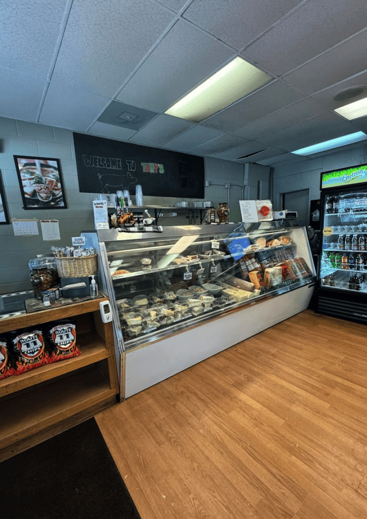 A bakery or cafe interior featuring a glass display case filled with baked goods and pastries under bright overhead lighting.