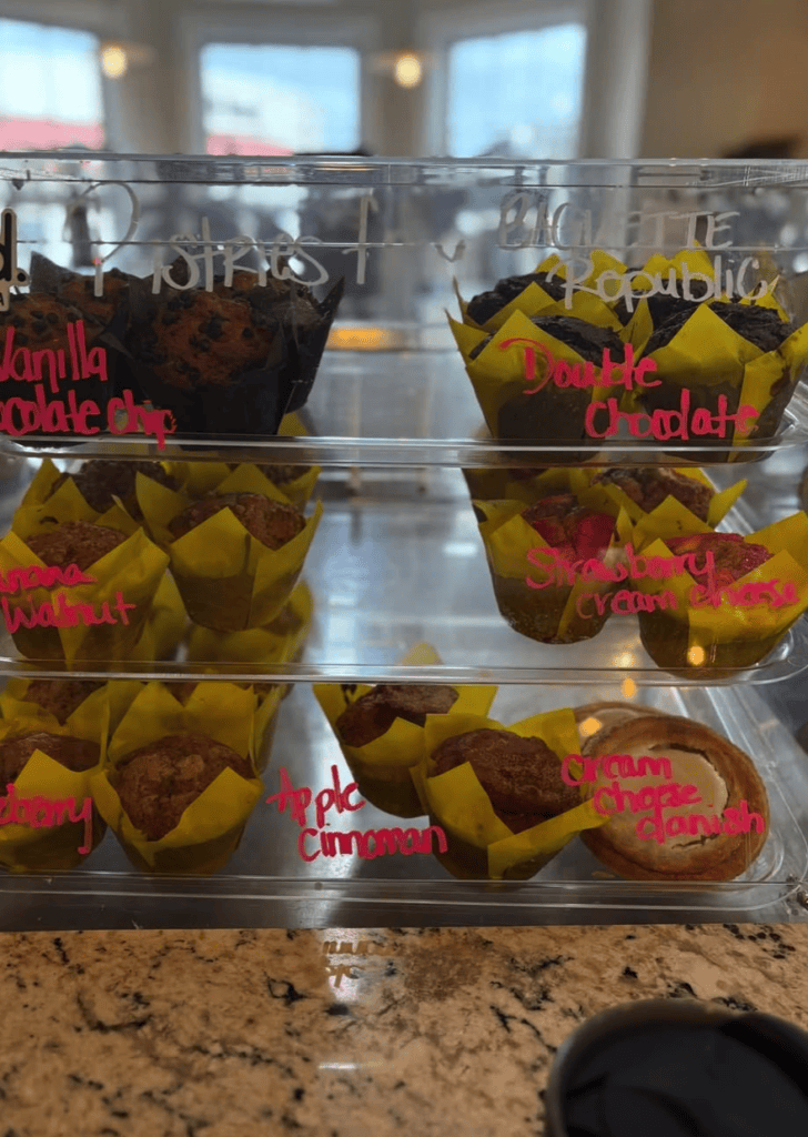 Prize-winning apples with red ribbons displayed in clear containers on a kitchen counter with windows and countertops visible in the background.
