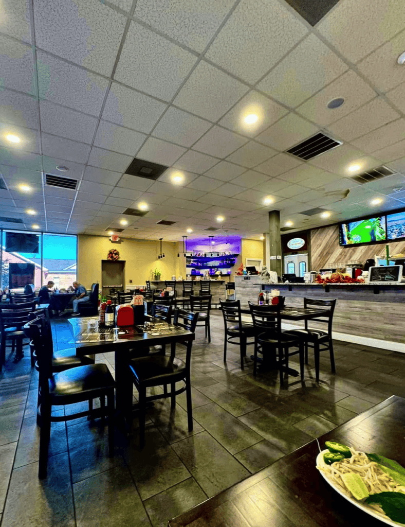 An indoor restaurant or casual dining establishment with black tables, bar seating, and modern lighting fixtures in a well-lit space.