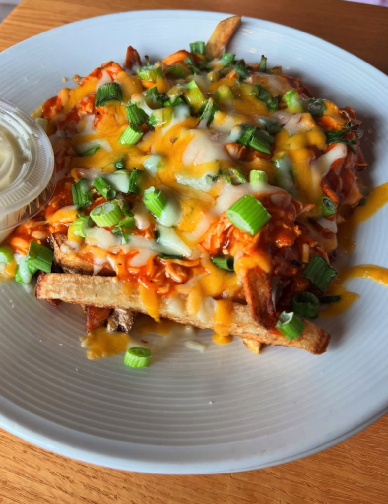 A close-up overhead shot of loaded nachos with melted cheese, diced peppers, and green onions on a light blue plate.