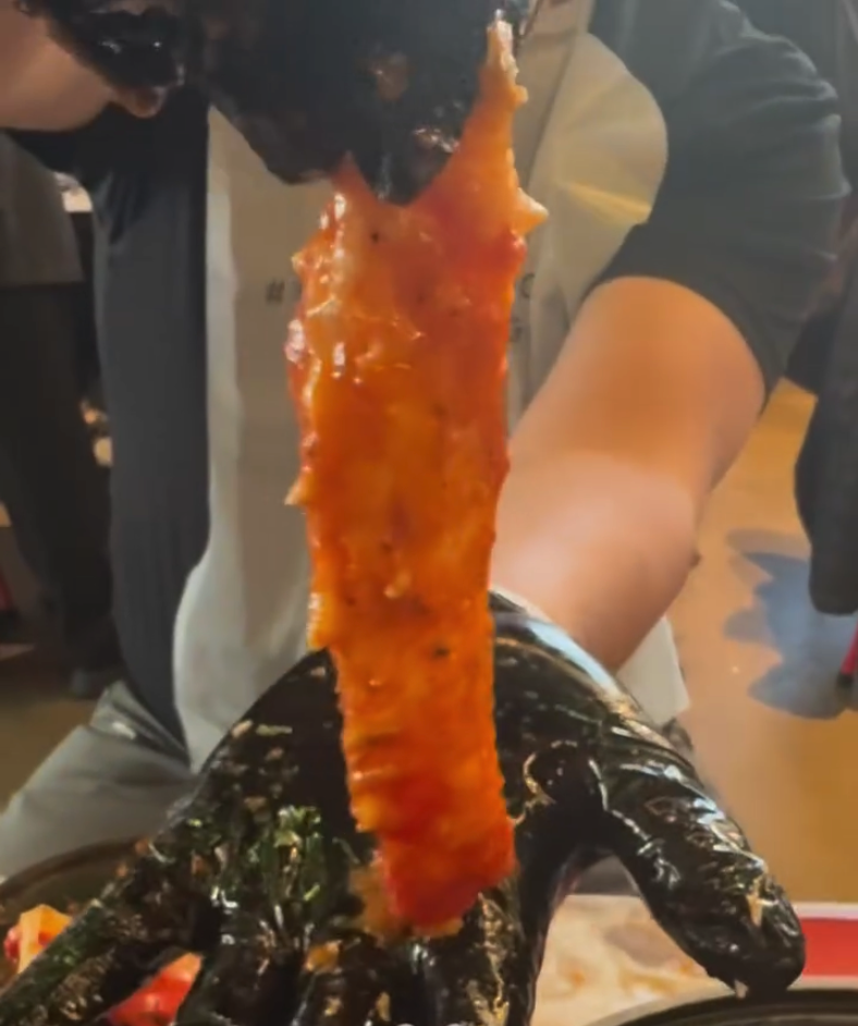 A close-up shot of a freshly made amber-coated candy apple being held up, showcasing its glossy caramel coating.