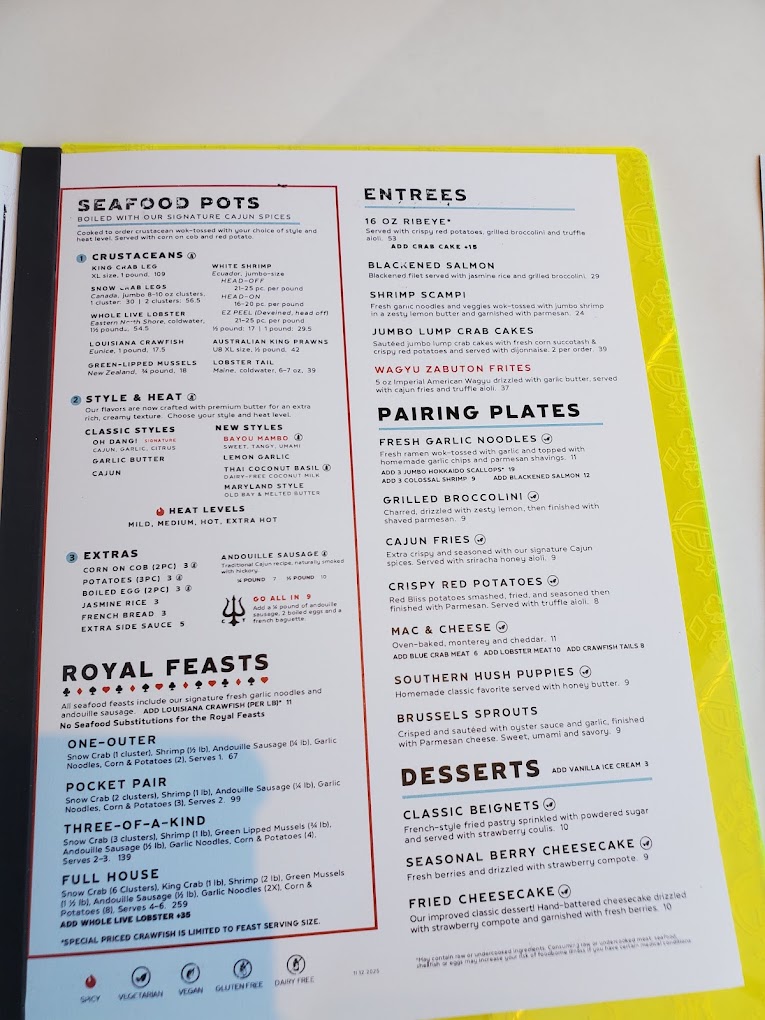 A laminated restaurant menu with yellow borders displaying various food categories including seafood pots, entrees, pairing plates, and desserts in a clean, organized layout.