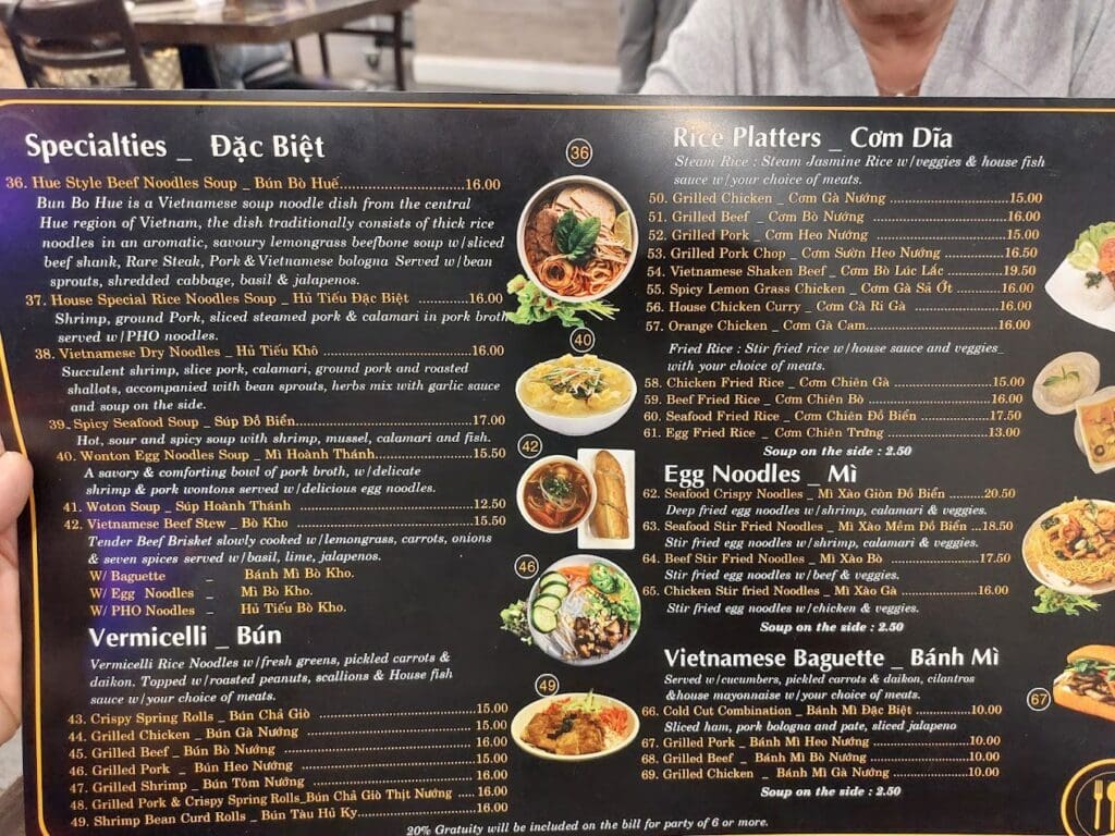 A dark-themed restaurant menu featuring Vietnamese noodle and rice dishes with food photography and descriptive text.
