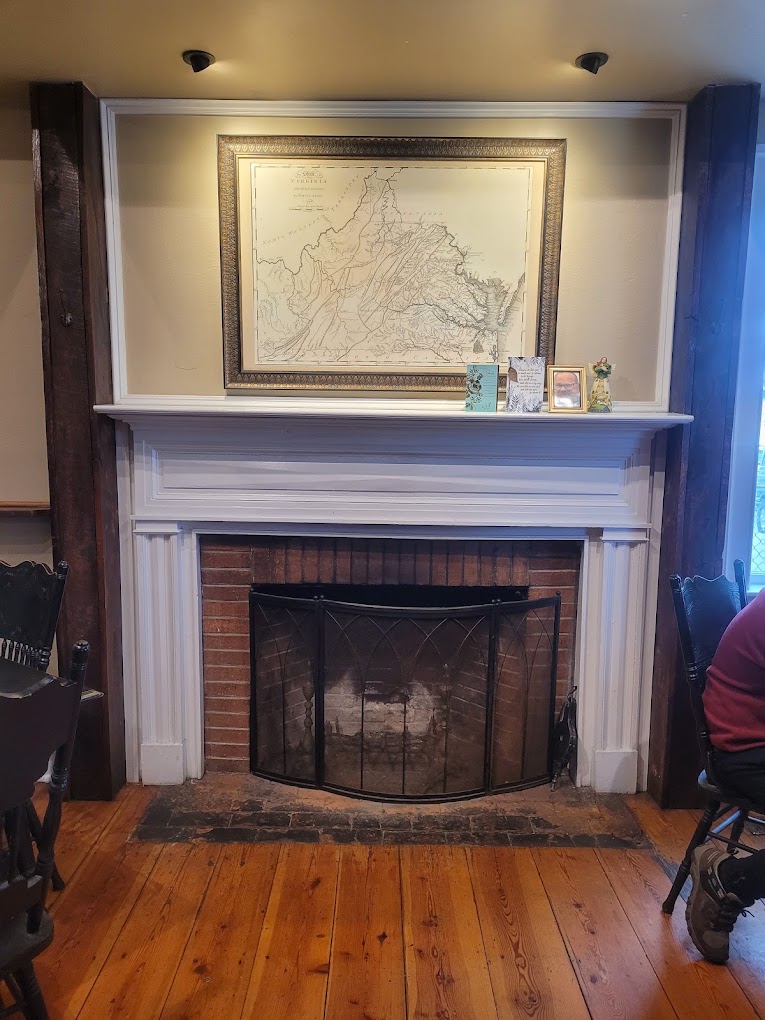 A residential fireplace with a white mantelpiece, brick surround, and a framed map artwork displayed above in a well-lit home interior.