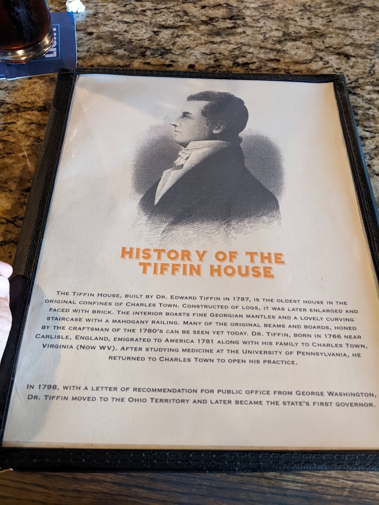 A framed historical portrait with accompanying informational placard about the History of the Tiffin House is displayed on a granite surface.