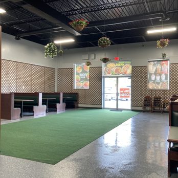 A modern indoor training or sports facility featuring artificial turf flooring, computer workstations, and geometric wall paneling under bright overhead lighting.