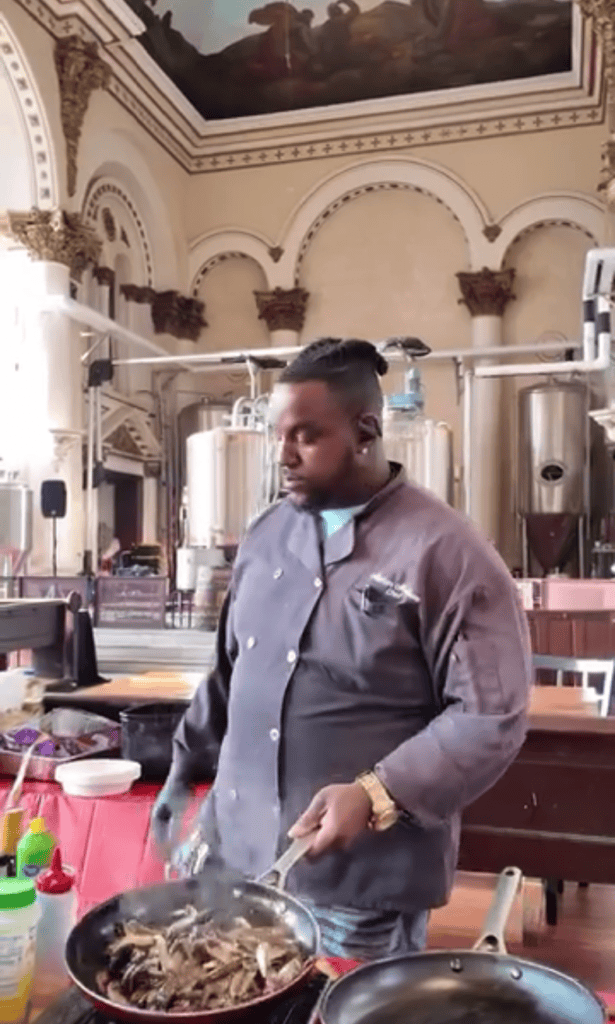 A chef conducts a cooking demonstration in an ornate, classical kitchen venue with elegant architectural details.