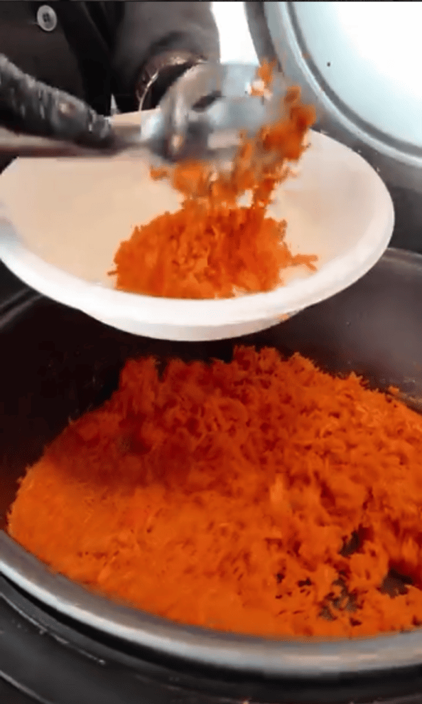 A close-up shot of someone grating fresh paprika powder onto a white plate in a kitchen setting.