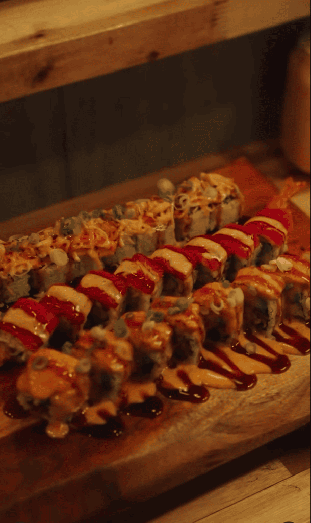 Grilled meat and vegetable kebabs arranged in rows on a wooden cutting board under warm indoor lighting.