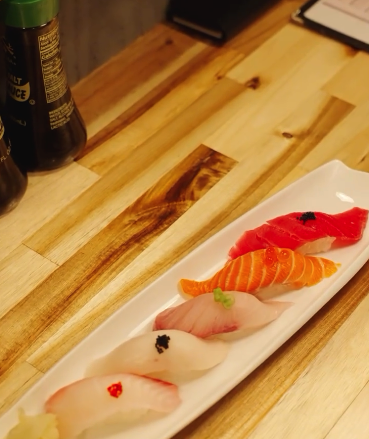 Raw fish fillets and ingredients arranged on a wooden cutting board during food preparation, photographed from above.