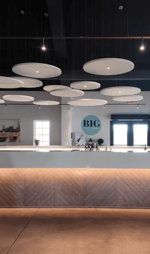 A modern restaurant or café interior featuring a sleek wooden counter with contemporary pendant lighting fixtures suspended from a dark ceiling.