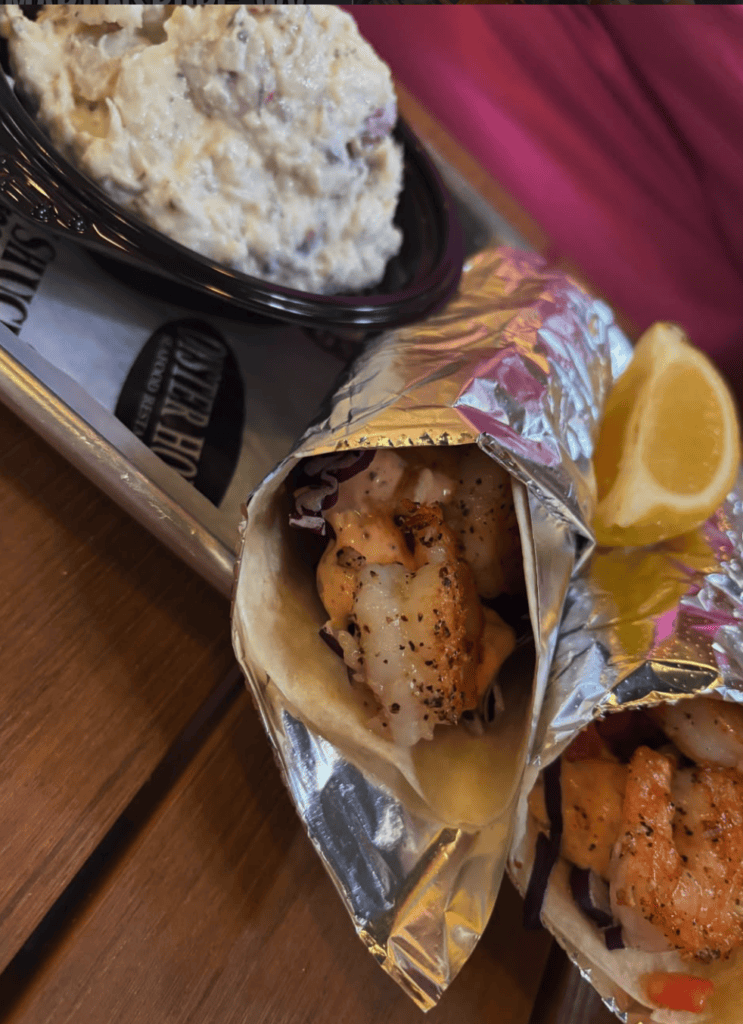 Close-up of freshly baked muffins wrapped in decorative paper with lemon slices and a bowl of batter on a wooden surface.