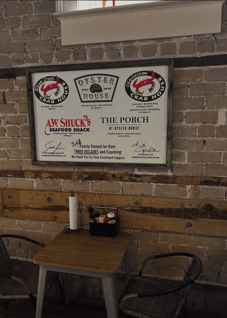 An interior shot of a rustic venue or bar featuring a decorative sign mounted on exposed brick wall above wooden furniture.