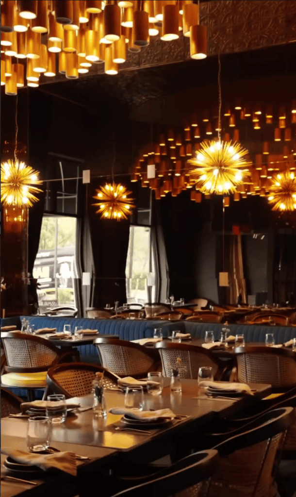 An elegant upscale restaurant or event venue lit by golden pendant lights with a formally set long dining table ready for service.