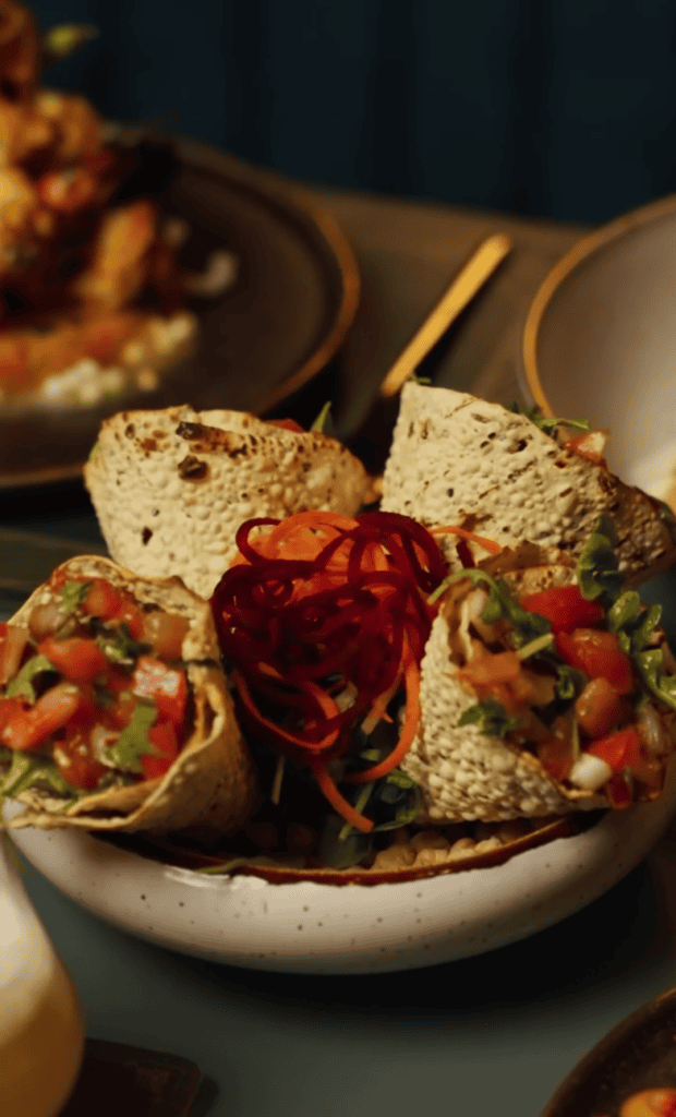 A close-up overhead shot of freshly prepared bruschetta appetizers arranged on a white ceramic plate in a dimly lit dining setting.