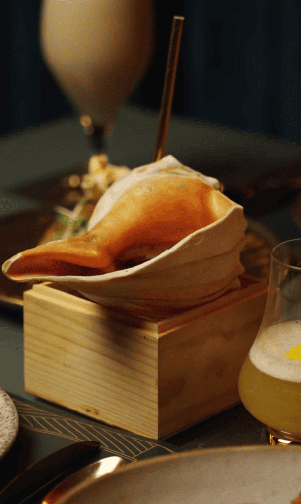 An elegantly plated gourmet dessert served in a wooden box with a spoon on a dark table, showcasing fine dining presentation.