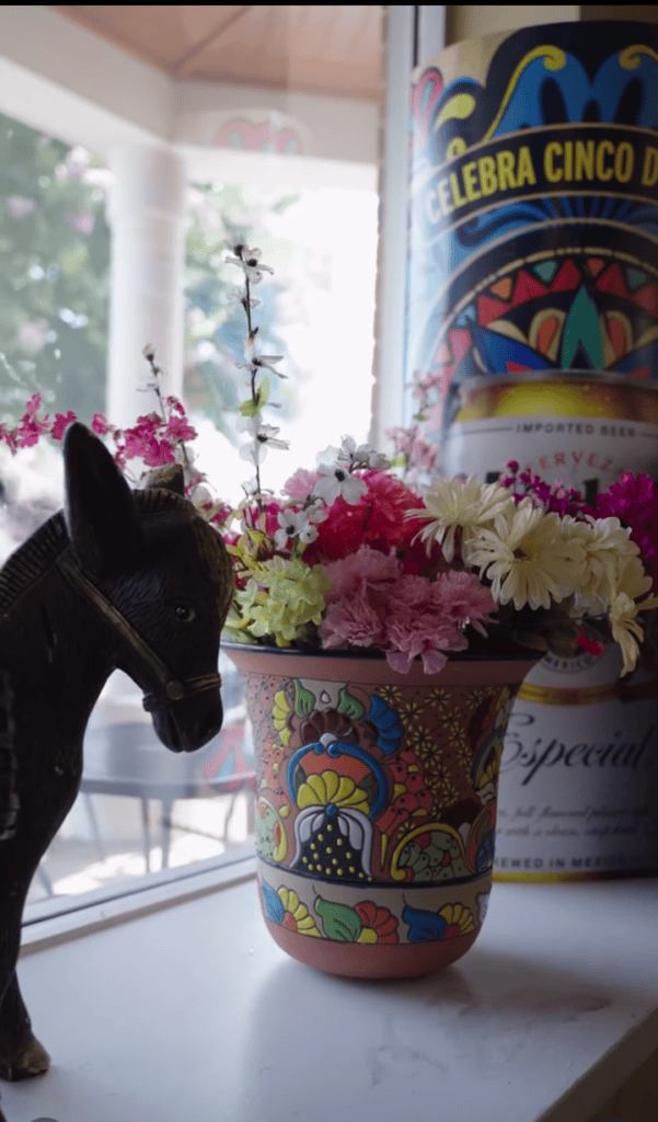 A black horse statue or figure is displayed next to colorful flower arrangements and a decorative beer bottle in what appears to be an indoor venue or fair setting.