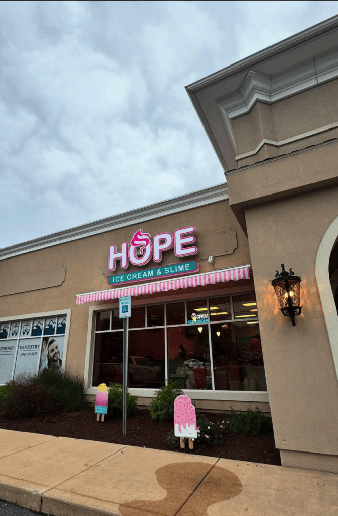 A storefront with a red 'HOPE' sign displayed prominently on its beige facade during daytime.
