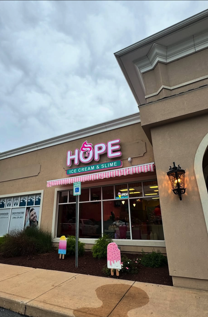 A storefront with a red 'HOPE' sign displayed prominently on its beige facade during daytime.