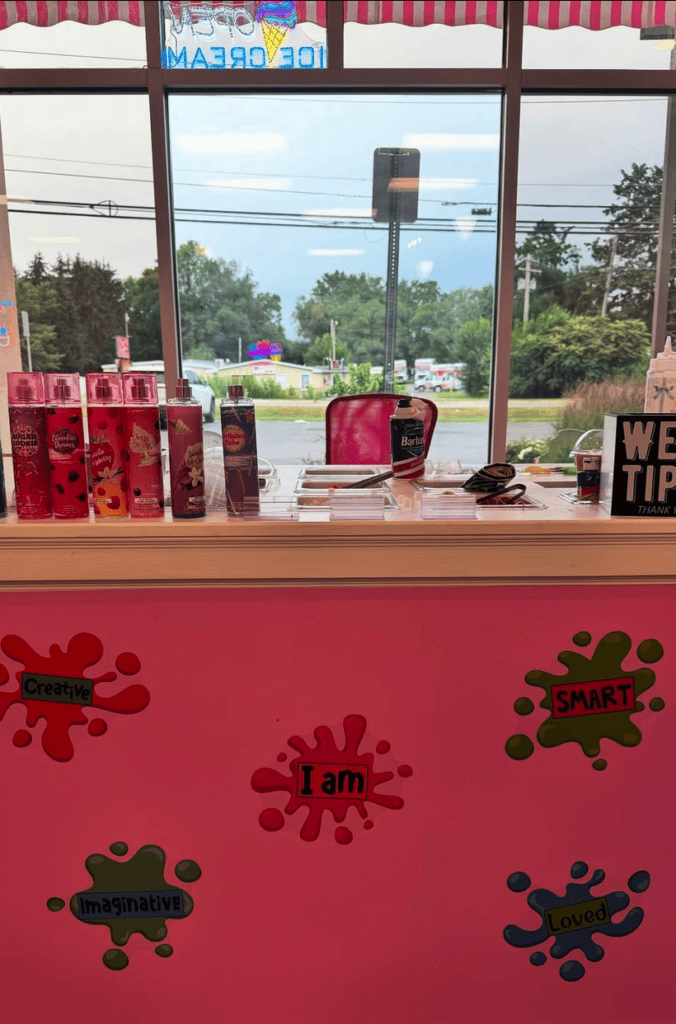 A storefront window display featuring red fabric with decorative virus-shaped cutouts in various colors, showcasing merchandise on shelves behind glass.
