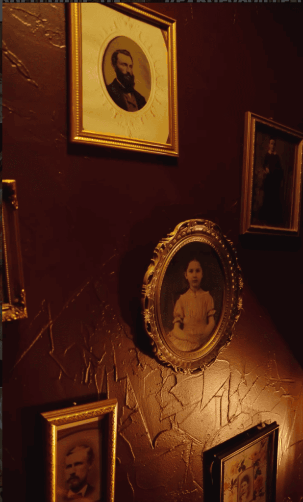 A collection of framed historical portraits hung on a deep burgundy wall, featuring ornate gold and decorative frames in varying sizes.