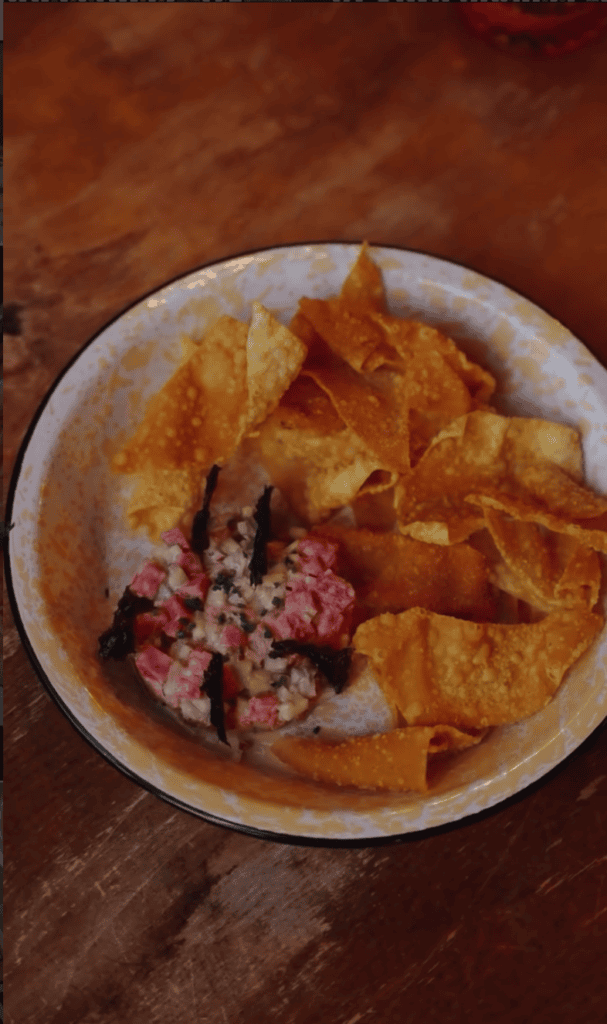 A plate of crispy tortilla chips topped with seasoned ground meat served on a white plate against a warm wooden surface.