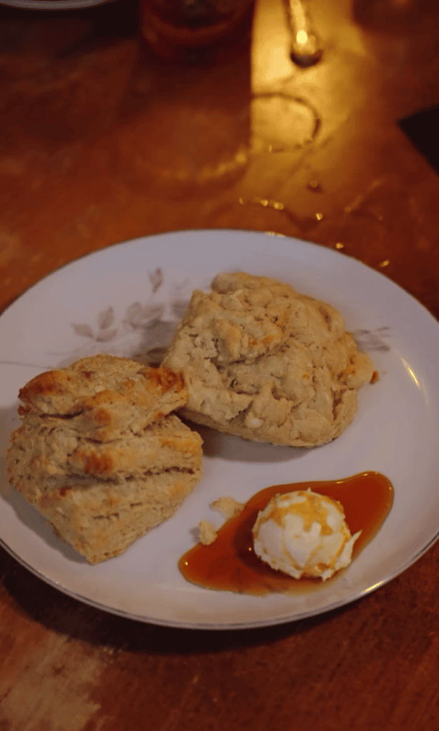 A white plate featuring several freshly baked cookies and pastries arranged artfully with a beverage visible in the background.