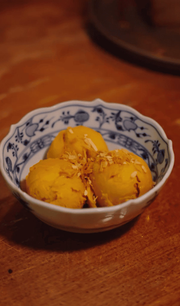 A close-up of golden fried potato cubes served in a traditional blue and white patterned ceramic bowl on a wooden surface.