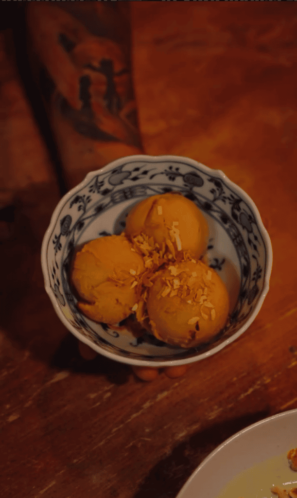 A close-up overhead shot of golden fried dumplings served in a decorative blue and white ceramic bowl on a wooden surface with warm ambient lighting.