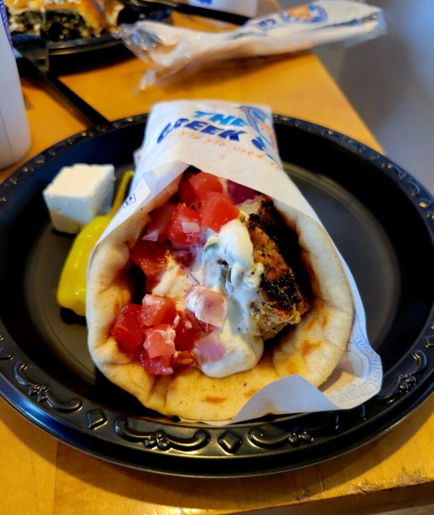 A gourmet flatbread appetizer topped with melted cheese, fresh tomatoes, and cream sauce is served on a decorative black plate at an upscale dining establishment.
