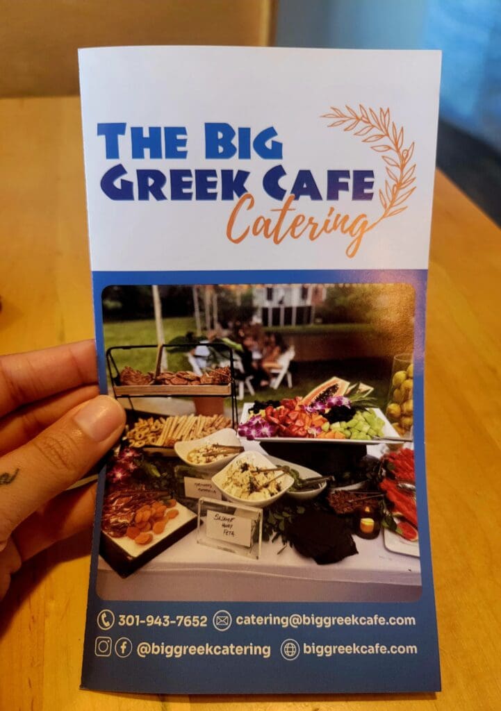 A business card for 'The Big Green Cafe Catering' featuring an outdoor catering event photo with tables and lawn setup.