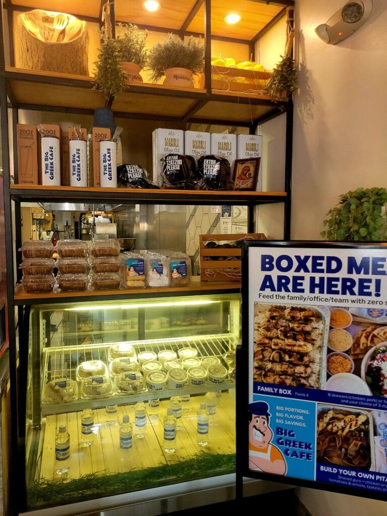 A retail display case showcasing boxed food products and merchandise on illuminated shelves with signage indicating boxed items are available.