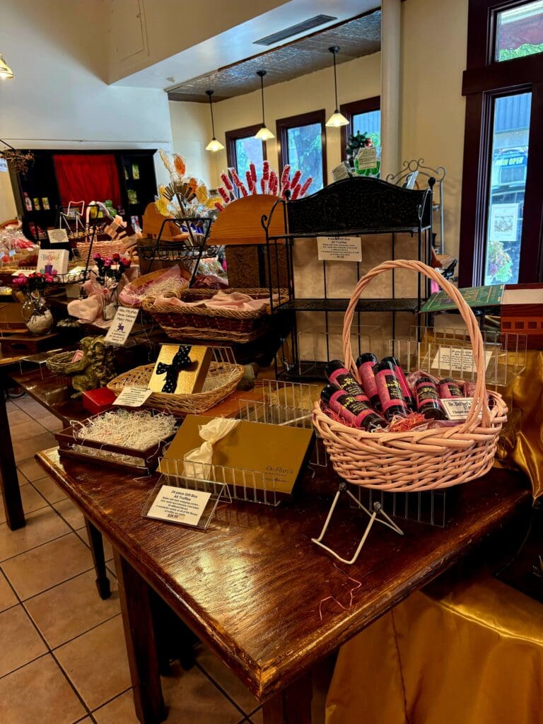 An indoor craft fair or artisan market display featuring handmade items including a prominent wicker basket on wooden tables with various goods and signage.