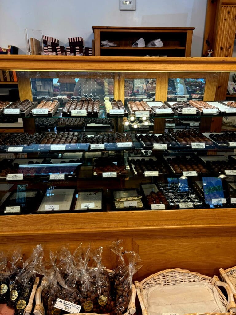 A wooden display cabinet filled with organized collectibles including figurines, model vehicles, trading cards, and various memorabilia arranged on multiple shelves.