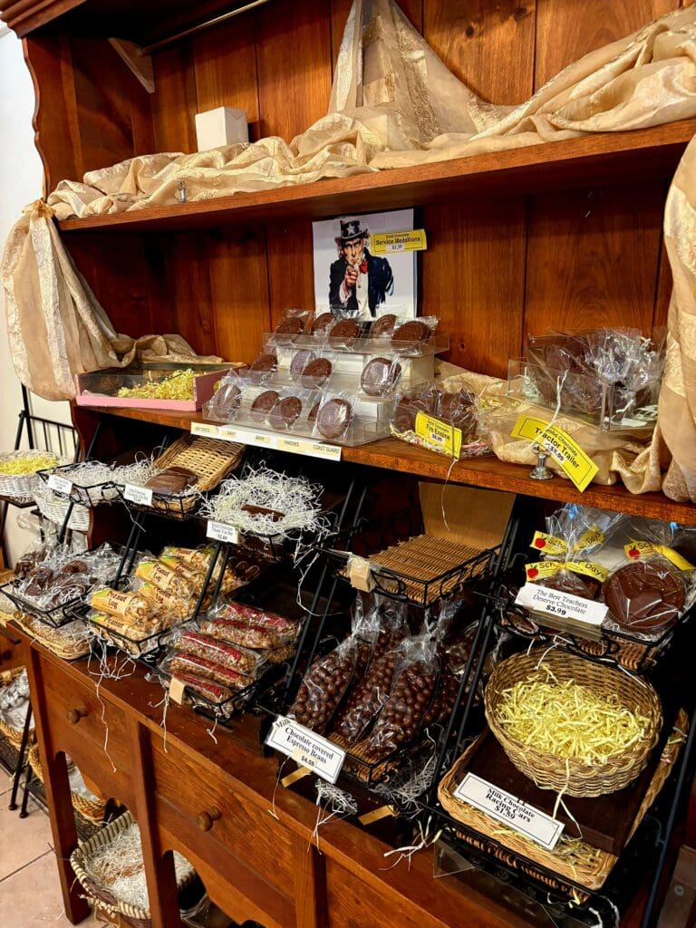 A wooden pantry shelf displaying various packaged foods, baked goods, and storage containers organized across three tiers.